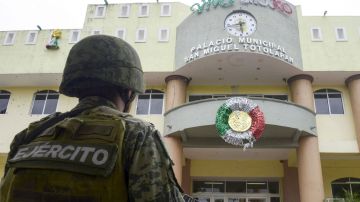 Un miembro del Ejército Mexicano de guardia frente a la fachada acribillada a balazos de la Municipalidad de San Miguel Totolapan.