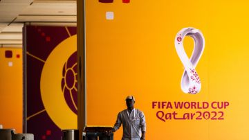 Un trabajador mueve un basurero más allá de los carteles del torneo de fútbol de la Copa Mundial de la FIFA Qatar 2022 fuera del Centro de Medios Principal (MMC) en Doha.