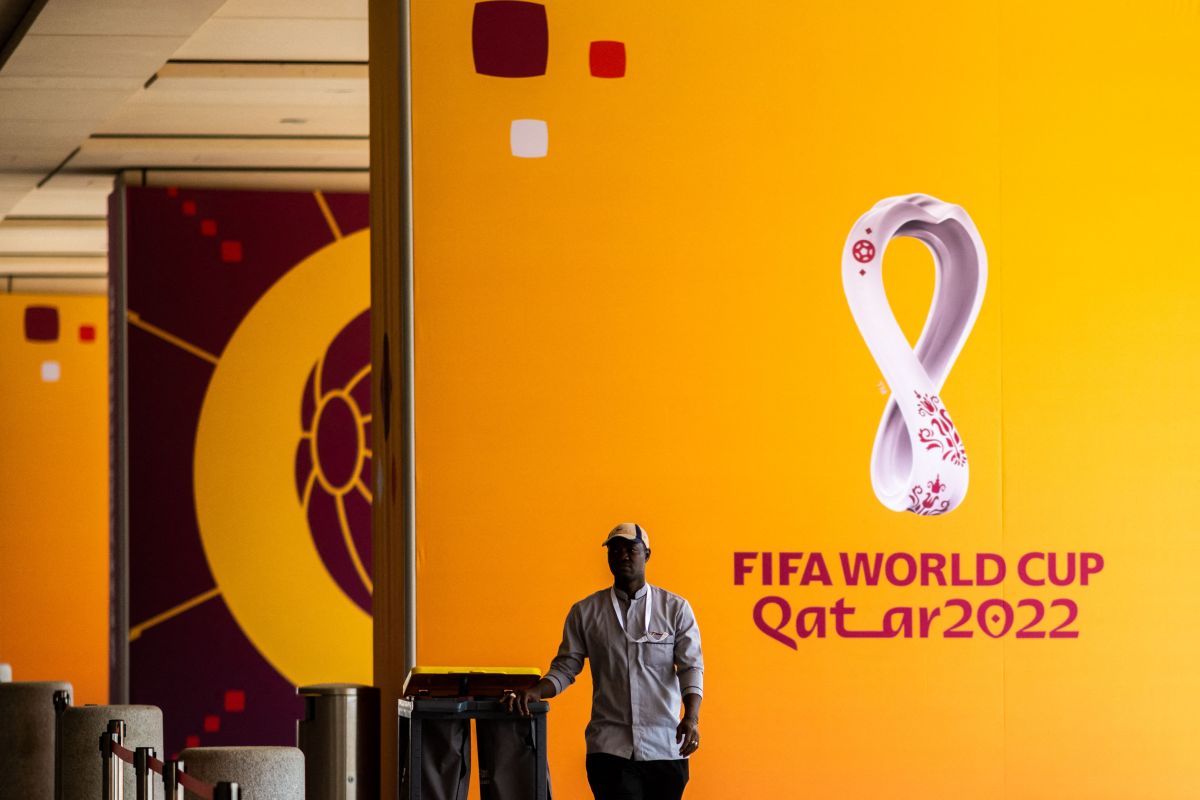 Un trabajador mueve un basurero más allá de los carteles del torneo de fútbol de la Copa Mundial de la FIFA Qatar 2022 fuera del Centro de Medios Principal (MMC) en Doha.