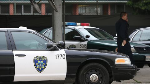 OAKLAND, CA - DECEMBER 06: An Oakland Police officer walks by patrol cars at the Oakland Police headquarters on December 6, 2012 in Oakland, California. Oakland City officials have come to an agreement to forfeit broad power over the Oakland Police Department to a court-appointed director to avoid federal takeover. The new compliance director would have the power to seek approval from a judge to fire the police chief. (Photo by Justin Sullivan/Getty Images)