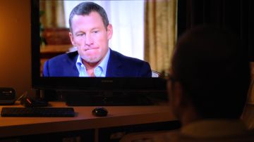 Una ilustración fotográfica muestra a un hombre mirando un televisor que muestra a la estrella del ciclismo en desgracia Lance Armstrong siendo entrevistado por Oprah Winfrey el 17 de enero de 2013 en Kensington, Maryland.