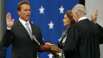 Arnold Schwarzenegger es juramentado como el 38º gobernador de California por el presidente del Tribunal Supremo de California Ronald George mientras la esposa de Schwarzenegger, Maria Shriver mira, el 17 de noviembre de 2003 en Sacramento, California.