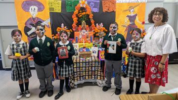 La maestra Florencia Terán y estudiantes de la escuela Our Lady of Guadalupe del este de Los Ángeles muestran su altar y decoraciones del Día de los Muertos. (Jacqueline García/La Opinión)