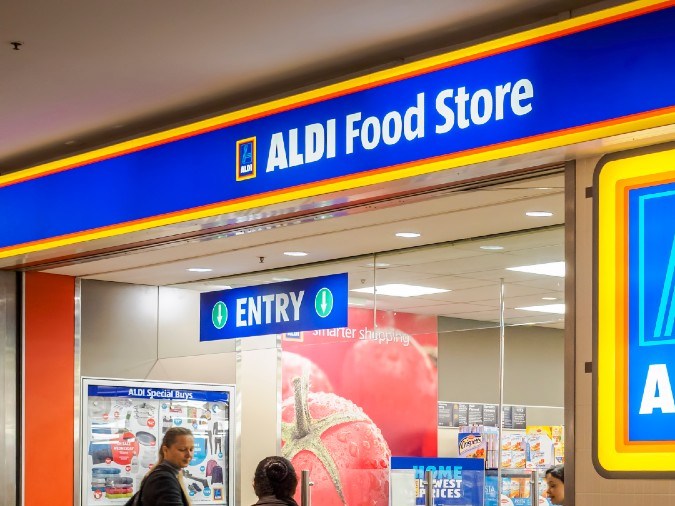 Imagen del acceso de una tienda Aldi en la que se ven gente formada para ingresar.