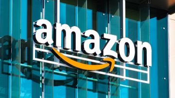 Imagen de un logotipo de la empresa Amazon en un muro de cristales azules.