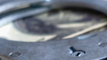 Imagen de unas esposas sobre varios billetes.