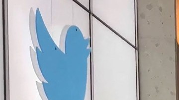 Una foto de Elon Musk en medio de un pasillo con escritorios y un logotipo de Twitter.