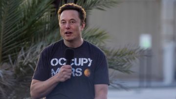 Imagen del multimillonario Elon Musk en una camiseta negra, con un micrófono en la mano.