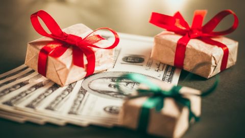 Imagen de tres cajas de regalo en medio de billetes.