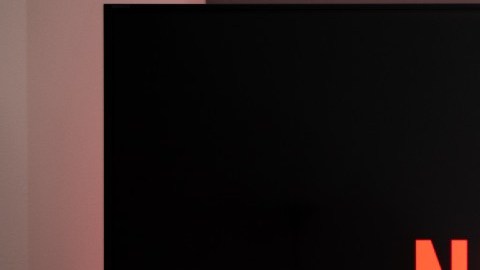 Imagen de una persona que mantiene sus pies sobre una mesa frente a una pantalla en la que se ve un logotipo de la plataforma Netflix.