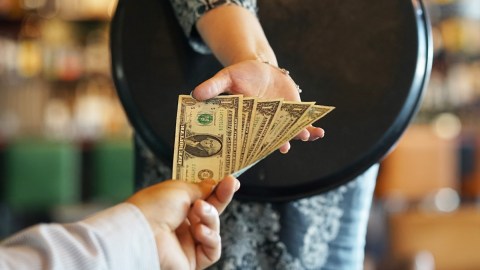 Imagen de una persona que da billetes a otra como propina.