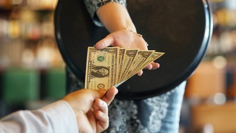 Imagen de una persona que da billetes a otra como propina.