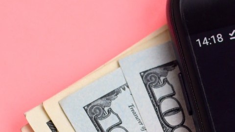 Imagen de un teléfono celular con un logotipo de TikTok y varios billetes.
