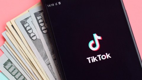 Imagen de un teléfono celular con un logotipo de TikTok y varios billetes.