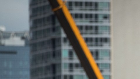 Imagen de una persona que trabaja subida en un andamio, en una obra en construcción.