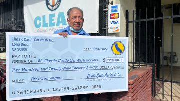 Anselmo Leyva, trabajador de lavados de carros, muestra el cheque que obtuvieron tras una denuncia por robo de salarios. (Cortesía)
