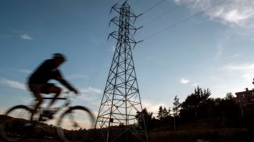 A bicyclist rides passed high-tension power lines in Mill Valley, California as a statewide blackout continues on October, 10, 2019. - More than a million Californians were without electricity due to pre-emptive blackouts October 10, 2019, but localized fires broke out as hot, windy conditions spread south toward Los Angeles. Some 600,000 customers in northern California were in the dark after Pacific Gas & Electric began switching off power the previous day, in a bid to prevent a repeat of last year's catastrophic inferno which killed 86 people. (Photo by Josh Edelson / AFP) (Photo by JOSH EDELSON/AFP via Getty Images)