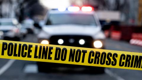 Police tape is seen in front of a police vehicle as Manuel Oliver displays a banner calling on government officials to prioritize gun violence prevention from a construction crane near the White House in Washington, DC, on February 14, 2022. - Olivers son Joaquin Oliver was killed in the Parkland School shooting four years ago today. (Photo by Stefani Reynolds / AFP) (Photo by STEFANI REYNOLDS/AFP via Getty Images)