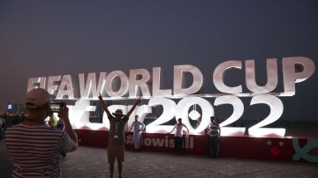 Aficionados en Qatar tomándose fotos con un letrero de la Copa del Mundo 2022.
