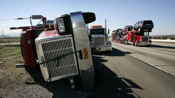RANCHO CUCAMONGA, CA - JANUARY 24: A wind-toppled big rig truck lies on its side along the Interstate 15 freeway as powerful Santa Ana Winds continue to cause problems on January 24, 2006 near Rancho Cucamonga, California. Numerous trucks and trailers have been over-turned on freeways and wildfires have ignited and are being fanned by high winds with gusts up to around 70 miles-per-hour. (Photo by David McNew/Getty Images)
