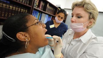 Felina martinez (L) is checked by dentist Irina Rayfeld from Commerce Dental during a free clinic to provide some healthcare to the one in four Californians who lack health insurance and services, at the ICDC medical training college in Los Angeles on March 24, 2010. The White House said it was confident President Barack Obama's health reform law had a solid legal foundation after 14 states vowed to challenge it on constitutional grounds. As soon as Obama signed the historic legislation into law on Tuesday, marking a famous political triumph, the group of state governments which oppose the plan lodged a flurry of legal challenges. Virginia filed suit claiming the health care package violates the US Constitution by requiring every citizen to buy health insurance or pay a fine. Thirteen other states issued challenges claiming that the new law violates the 10th amendment to the Constitution, which reserves powers not specifically granted to the federal government to the states. AFP PHOTO/Mark RALSTON (Photo credit should read MARK RALSTON/AFP via Getty Images)