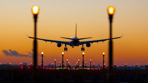 Imagen de un avión mientras realiza una maniobra de aterrizaje en una pista con luces iluminadas.