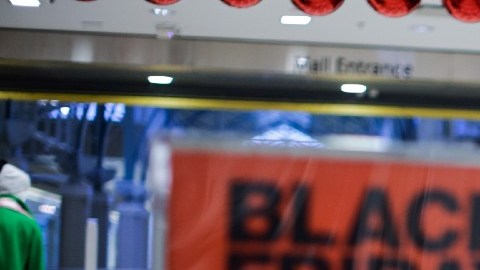 Imagen de una persona que se pasea por un centro comercial en medio de letreros de ofertas y descuentos.