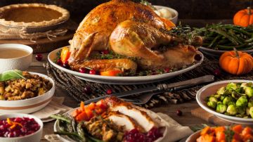 Imagen de una cena de Thanksgiving con varios platos servidos de pavo y varios tipos de verduras.
