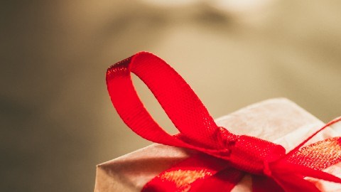 Imagen de varias cajas de regalo con moños de color rojo y verde, sobre fajos de billetes.