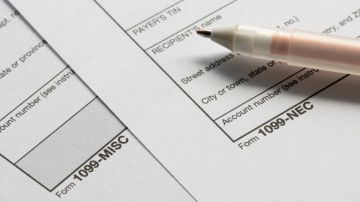 Imagen de las hojas de dos formularios para una declaración de impuestos, colocados uno sobre otro, y una pluma.