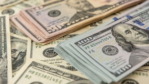 Imagen de varios fajos de billetes de dólar, puestos unos sobre otros.