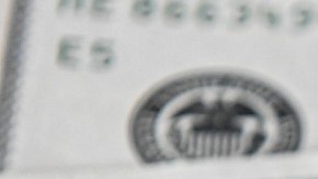 Imagen de tres billetes de dólares, uno encima de otro.