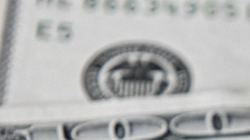 Imagen de tres billetes de dólares, uno encima de otro.