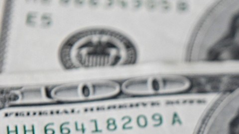 Imagen de tres billetes de dólares, uno encima de otro.