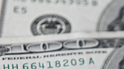Imagen de tres billetes de dólares, uno encima de otro.