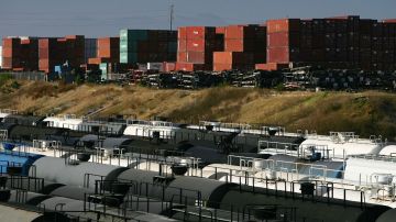 Imagen de un puerto en el que se ven contendores y vías de ferrocarril con vagones taque de combustible.