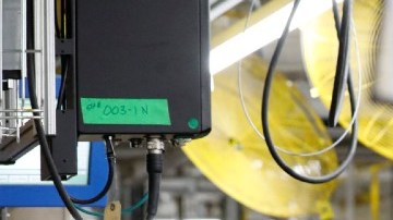 Imagen de dos personas que trabajan en una línea de ensamblaje automotriz.