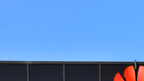 Imagen de un edificio en cuya parte superior hay un letrero con la imagen de la marca Huawei y una antena en la parte superior.