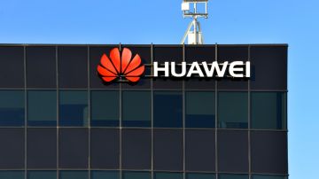 Imagen de un edificio en cuya parte superior hay un letrero con la imagen de la marca Huawei y una antena en la parte superior.