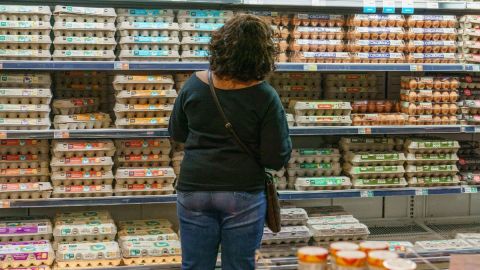 Imagen de una persona frente a un estante en el que se ven cajas con huevos.