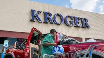 Imagen de la entrada de una tienda Kroger y de una persona que carga mercancía en una camioneta.