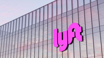 Imagen de un logotipo de la empresa Lyft en color rosa colocado en la fachada de un edificio.
