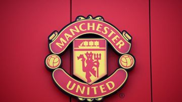Imagen del escudo del Manchester United, en un fondo de color rojo.