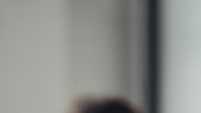 Imagen de una persona que carga una caja de cartón y en el fondo otra, fuera de foco, empaca para una mudanza.