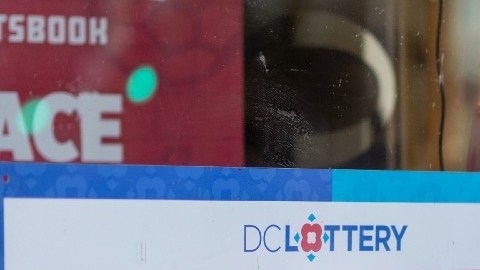 Imagen de la ventana de una tienda en la que se observa un letrero de venta de lotería Powerball y Mega Millions.