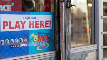 Imagen de la ventana de una tienda en la que se observa un letrero de venta de lotería Powerball y Mega Millions.