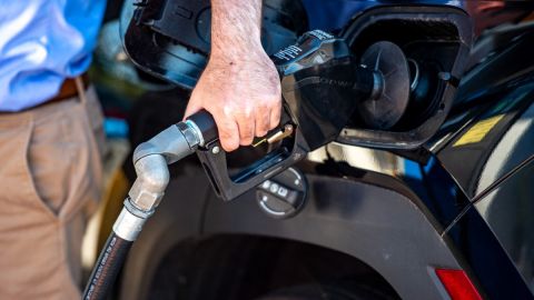 Imagen de una persona que toma una manguera de carga de gasolina.