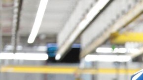 Imagen de una línea de producción de vehículos en donde una persona manipula un auto en fabricación.