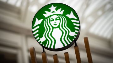 Imagen de un anuncio luminoso del logotipo de la cadena de café Starbucks en color verde y blanco.
