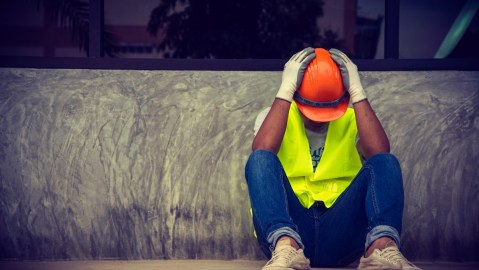 Imagen de un trabajador que está en el suelo con las manos en la cabeza.